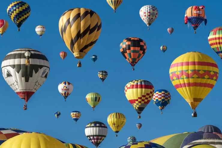 Una vasta distesa di mongolfiere colorate che fluttuano in un cielo azzurro.