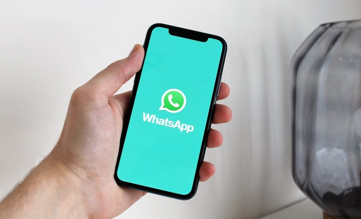 uomo con telefono in mano e logo whatsapp